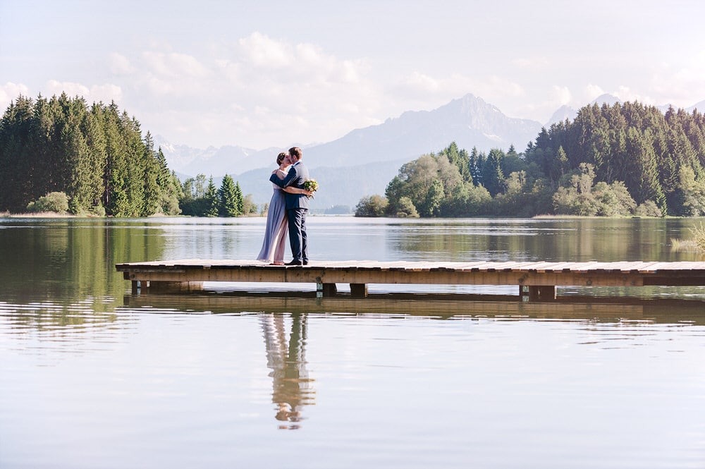 Hochzeitsfotograf Osnabrück Münster Bielefeld Moritz Fähse | Fotoshooting am See mit Brautpaar auf einem Steg vor den Alpen