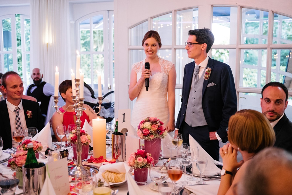 Brautpaar hält eine kleine Rede am Tisch vor der Party